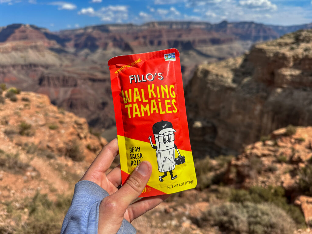 Fillo's Walking Tamales bean salsa road snack held in hand with Grand Canyon landscape in background