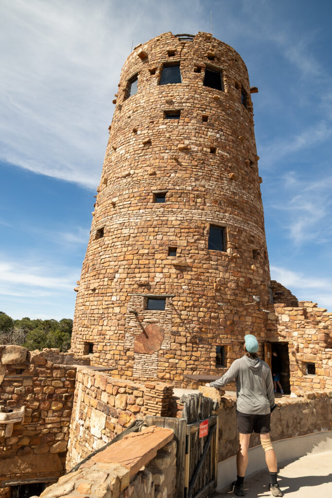 Person looking up at the Desert View Watchtower, a round stone structure designed by Mary Colter and built in 1932 based on Puebloan architecture. This is one of the best things to do in the Grand Canyon on the South Rim.