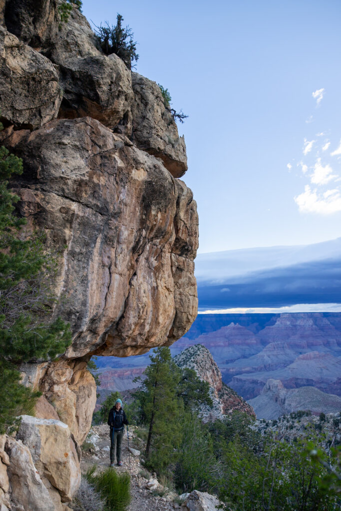 Hiker on the Grandview Trail at dawn ascending toward Coconino Saddle, with expansive canyon views and layered rock formations visible in the background