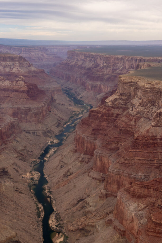 Aerial view of the Grand Canyon with the Colorado River winding through red rock formations and canyon walls