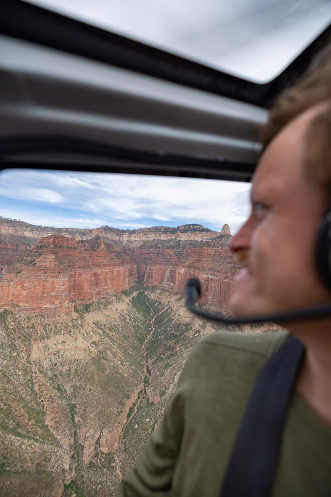 Elliot gazing out the helicopter window at the red rock formations and canyon landscape of the Grand Canyon below