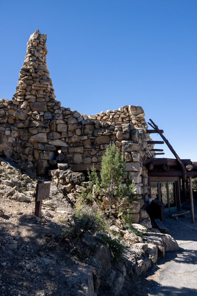 A tall stone structure with a stacked-rock cairn and wooden beam framework at Hermits Rest, Grand Canyon South Rim