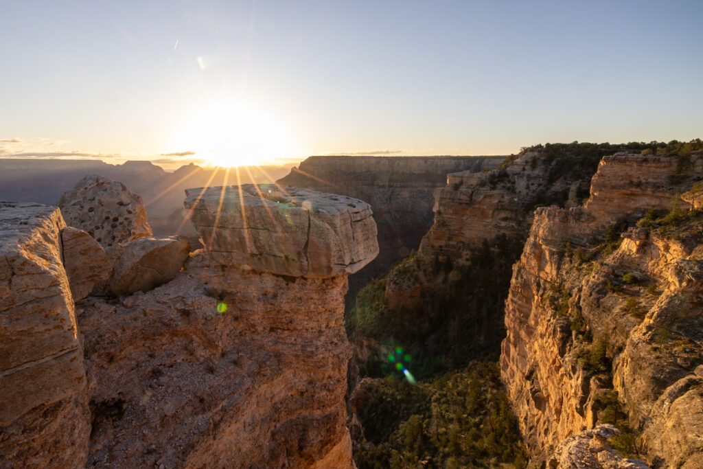 Sun rising over the Grand Canyon at Mather Point, illuminating the rocky canyon walls and distant plateaus