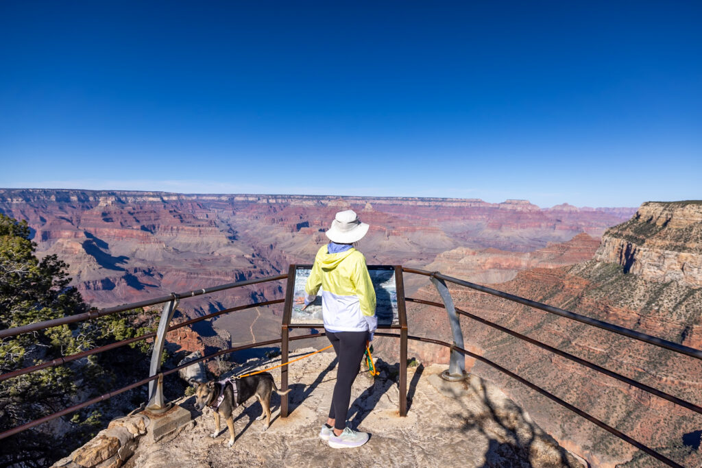 Jen and Ollie on the Rim Trail near Trailview Overlook, with expansive canyon views in the background. Walking the rim trail is one of the best things to do at the Grand Canyon.