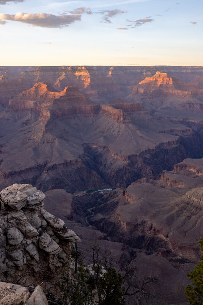 Golden light illuminates the layered rock formations and Colorado River of the Grand Canyon at sunrise, viewed from Pima Point on the Rim Trail