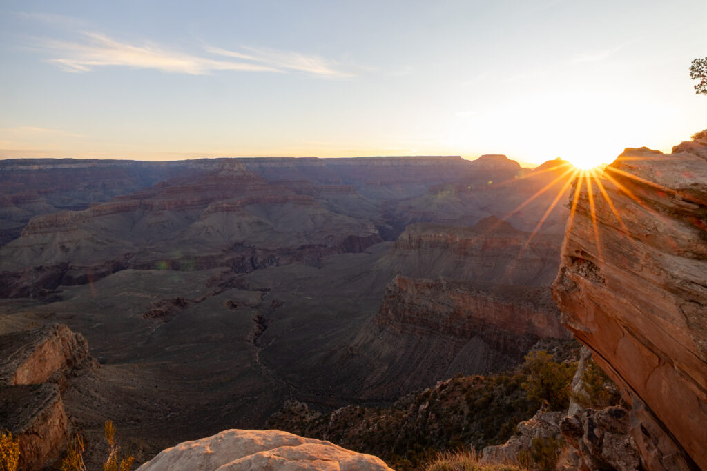 Sun rising over the Grand Canyon at Ooh Aah Point, illuminating the layered rock formations and canyon depths below