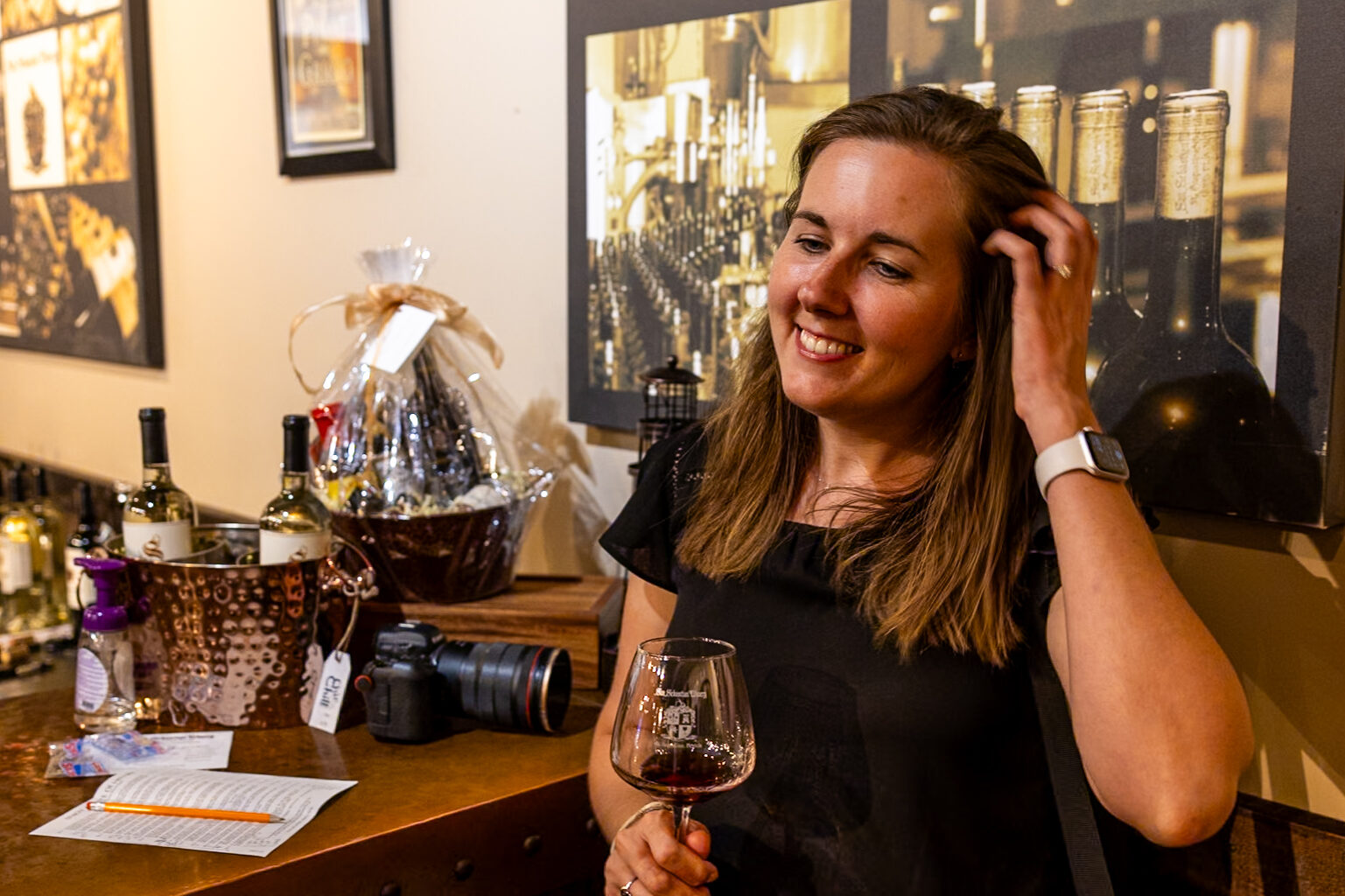 Jen enjoying a glass of wine at San Sebastian Winery tasting room, with wine bottles and displays visible behind her